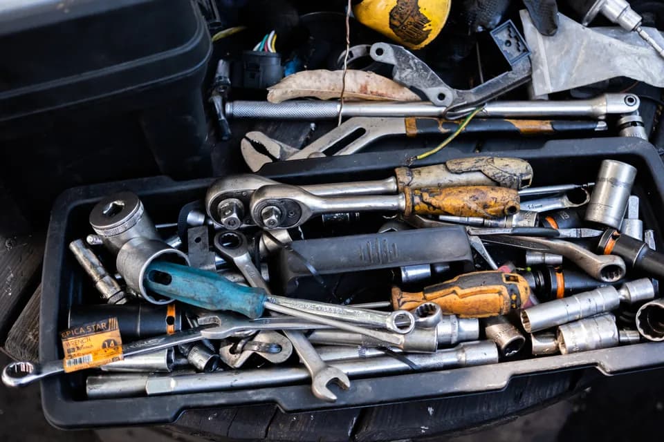 A well-used tray of ratchets, sockets, spanners and screwdrivers beside an engine